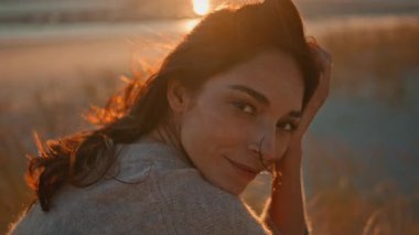 Güneşin doğuşunu gösteren güzel bir model ve yakın plan saçları var. Romantik kadın portresi doğada altın sabah güneşinin tadını çıkarıyor. Huzurlu hayalperest kadın gün batımında etrafındaki kuru otları rahatlatıyor..