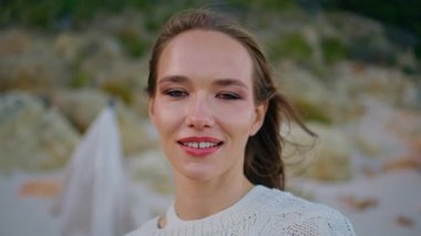 Portre, akşam manzarasında rahatlamış model kamera görüntüsü. Alacakaranlık doğasında esintili saçlarıyla poz veren güzel genç bir kadın. Kaygısız kız sahilde dinleniyor rüzgarlı havanın tadını çıkarıyor..