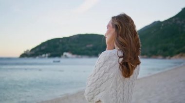 Sakin bir akşamda deniz kıyısında dikilen yalnız bir kadın. Romantik bayan güzel bir deniz ufkuna benziyor. Rahat gezgin, sahil doğasında sabahın tadını çıkarıyor. Kumral tek başına deniz manzarası seyrediyor..