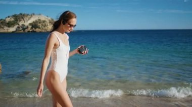 Deniz tatilinde müzik dinleyen bir kız güzel bir sahil kenarında yürüyor. Beyaz mayo giymiş kaygısız bir kadın plajda klasik kaset çalar tutuyor. Gülümseyen esmer, okyanus kıyısındaki kulaklıklardan keyif alır..