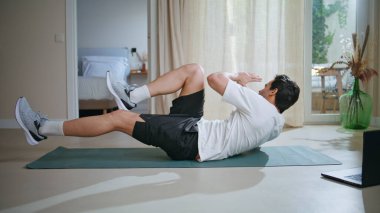 Spor adamı sabah antrenmanında yoga minderinde mekik çekiyor. Modern iç mekanlarda vücut gücüne odaklanan bisiklet egzersizleri yapan aktif bir adam. Dairede enerjik atlet eğitimi dayanıklılığı.