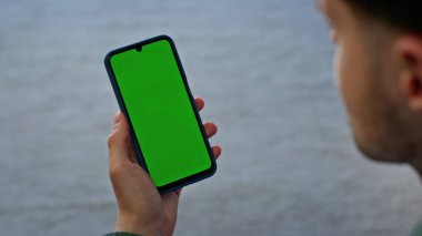 Akıllı telefon kullanıcısı konforlu bir dairede yeşil ekran görüntüsünü izliyor. Yumuşak halı odasında krom anahtarlı cep telefonu tutan ev adamı. Sadece cep telefonundan sosyal medyayı kontrol eden tanınmayan bir adam. 