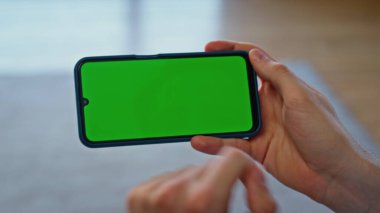 Dairenin kapanışında parmak şıklatma şablonu akıllı telefonu. Krom anahtar cihazlı kadın kullanıcı hafta sonu evde dinleniyor. Tanımlanamayan dinlenen kız yeşil ekranlı cep telefonu kullanıyor. 
