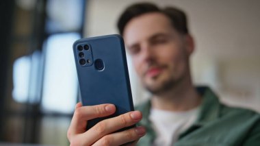 Bulanık bir adam cep telefonuna bakıyor. Yakın çekimde mesaj alıyor. Adam aydınlık dairede modern akıllı telefonu tutuyor. Tıraşsız gülümseyen menajer evde cep telefonundan mesaj okuyor. 