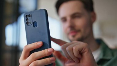 Neşeli öğrenci cep telefonunu evde yakın plan çekiyor. Mutlu rahat adam evde rahatlarken akıllı telefondan komik videolar izliyor. Bulanık adam sosyal ağlar uygulaması kullanarak cep telefonu ekranını tıklatıyor