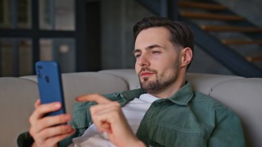 Akıllı telefondan kanepe yazıp ev ortamını yakından izleyen yalancı bir adam. Rahat iç mekanda cep telefonuyla dinlenen pozitif ssm çalışanı. Evcil erkek model, gün ışığında yalnız başına dinleniyor. 