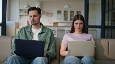 Dizüstü bilgisayar kullanan serbest çalışan çift iç mekanda çalışıyor. Odaklanmış karı koca birlikte oturup bilgisayar yazıyorlar. Aile içi internet gezintisi uzak bir yerde internetteki işten keyif alma 