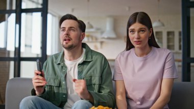 Aşırı sevinçli arkadaşlar televizyon maçı izleyip kanepede otururken heyecanlı hissediyorlar. Mutlu erkek kadın seviniyor TV şampiyonasında favori takımı kazanıyor. Duygusal çiftler alkışlıyor. 