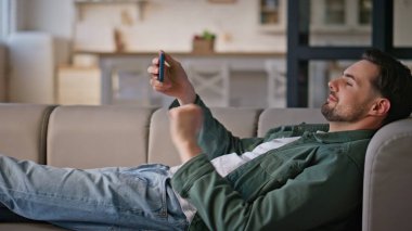 Kromakey akıllı telefondan hoşlanan bir adam. Kanepe oturma odasında takılan yeşil ekranlı cep telefonunu izleyen rahat adam. Apartman kanepesinde cep telefonunu dinleyen genç hippi. 