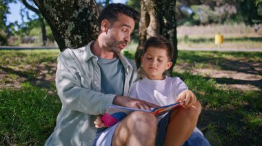 Orman yakınlarında yeşil çimlerde oturan sevimli bir aile kitabı okuyor. Sevimli küçük çocuk büyük bir ağacın altında babasıyla geçirdiği hafta sonu mutluluğunu ifade ederken eğleniyor. Sevgi dolu ebeveyn oğul ilişkileri 