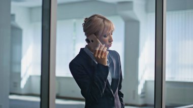 Ofis binasında cep telefonundan konuşan kendine güvenen bir iş kadını. Ciddi bir yönetici cam salonda iş görüşmesi yapıyor. Kendine güvenen profesyonel akıllı telefondan iş konuşmasına daldı