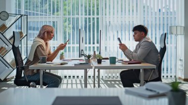 Ofiste dinlenen yorgun ve akıllı telefonlu iş arkadaşları. İş kadını işadamı kabine masasında kendini aşırı yüklü hisseden cep telefonlarına bakıyor. Takım çalışanları iş yerinde çalışmaktan yoruldu. 