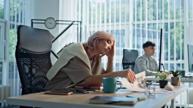 Yorgun iş kadını iş yerinde yakın plan oturuyor. Sıkılmış bir iş kadını gibi görünen bilgisayar monitörü açık panoramik dolapta klavye yazıyor. Çalışma alanı içlerinde aşırı çalışan yorgun bir yönetici