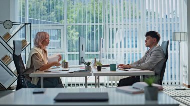 Ofis çalışanları panoramik iç mekanda masa başında oturmuş görevleri çözüyorlar. Yorgun adam ellerini uzatıp bilgisayara bakıyor. Sarışın iş kadını belge okuyor. Işık kabinesinde proje üzerinde çalışan iki kişi