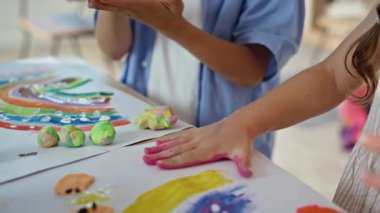 Okul kızı elle resim yapıyor kağıt üzerinde el izi yaratıyor. Sanat atölyesinde el yapımı sanat eserleri yapan mutlu bir öğrenci. Sanatsal duygusal çocuk sınıfta renkli resimler çizmekten hoşlanıyor.