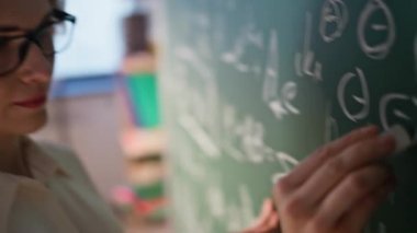 Matematik okulunda karatahtaya yazı yazan yakın eğitimci. Tahtada formülleri açıklayan matematik teorisi öğreten zeki bir kadın. Üniversite sınıfında gözlüklü bayan profesör..