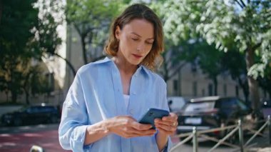 Sunny Sokağında duran akıllı telefonu kullanan bir kadın bekliyor. Gülümseyen bayan dışarıda cep telefonuyla vakit geçiriyor. Şehir merkezinde kendine güvenen orta yaşlı kadın cep telefonuna bakıyor