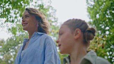 Rahatlamış anne kızı park alanında yürüyor. Orta yaşlı anne tatlı çocuk, yemyeşil doğayla iç içe. Mutlu kadın kız birlikte tatilin tadını çıkarıyor. Gülümseyen kadın ebeveyn çocuk gezintisi