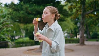 Güneşli parkta sabun köpüğü oynayan bir çocuk. Sevimli küçük çocuk yeşillik doğasında dinlenerek çocukluğundan zevk alıyor. Yeşil meydanda duran sarışın güzel kız yazı geçiriyor. Tasasız anlar konsepti