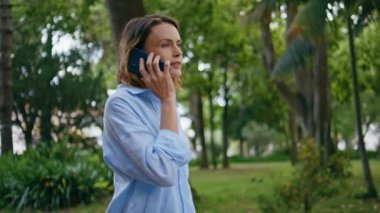 Rahat bir kadın parkta dolaşırken cep telefonunu kapatıyor. Gülümseyen çekici bayan akıllı telefon bahçesinde konuşuyor. Sakin bir iş kadını cep telefonuyla konuşuyor ve tropikal doğanın tadını çıkarıyor. 