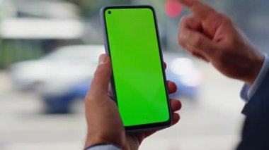 Büyük pencerenin yakınında yeşil ekran akıllı telefona dokunan erkek elleri. Bilinmeyen yönetmen internet bilgilerini internette araklıyor. Profesyonel işçi parmakları kromakey cep telefonunu kaydırıyor