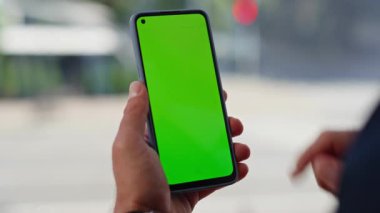 Şehir manzaralı mekanda akıllı telefon yeşil ekran tarama uygulaması. Kafede krom anahtarlı cep telefonu tutan tanınmayan bir iş adamı. Model etkileşimi için boş ekran