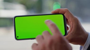 Panoramik pencerede yeşil ekran akıllı telefona dokunmak. İşadamı, e-postayı izleyen yatay cep telefonunu dinliyor. Kromakey cep telefonunu evde tek başına tutan tanınmayan bir yönetici.