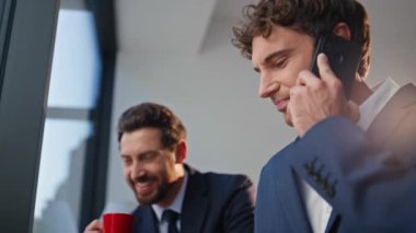 Akıllı telefondan iyi haberler duyan neşeli iş adamları ofis koridorlarını kapatıyorlar. Espresso bardağının sahibi erkek meslektaşım başarıya duygusal tepki veriyor. İş adamına olumlu çağrı