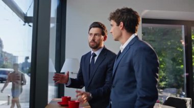İş ortakları ofis lobisinde konuşurken şehir manzarasını yakından izliyorlar. Kahve molasında duygusal konuşan aktif iş adamları. İki meslektaş dost iletişimi kuruyor