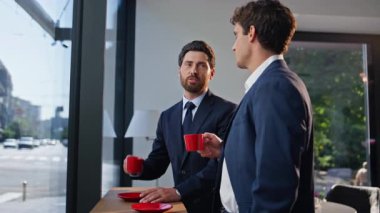 Rahat iş ortakları lobide birlikte kahve içiyorlar. Takım elbiseli meslektaşlar panoramik pencere kafesinde mola veriyor. Resmi olmayan toplantıda gülümseyen mutlu profesyoneller. 