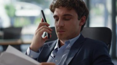 Ofis portresindeki kağıtları inceleyen adam aranıyor. Akıllı telefondan konuşan mutlu iş adamı gülümseyen yakın tebessümle mali rapor sunuyor. Pozitif yöneticinin elinde telefon görüşmesi belgeleri var