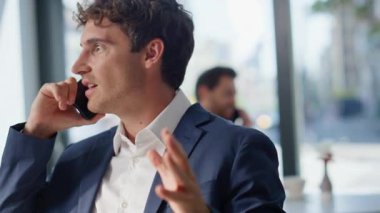 Kafede oturan işadamları cep telefonlarını kapatıyorlar. Duygusal takım elbiseli adam panoramik ofis kantininde akıllı telefon konuşması yapıyor. Heyecanlı bir iş adamı cep telefonuyla el kol hareketi yapıyor.