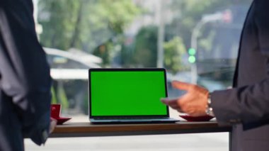Şehir manzaralı kafede yeşil ekran laptoptan bahseden kimliği belirsiz iş adamları. Tanımlanamayan iş ortakları ofis lobisinde çay molası veriyorlar ve tezgahta da bilgisayar var. İki işadamı.