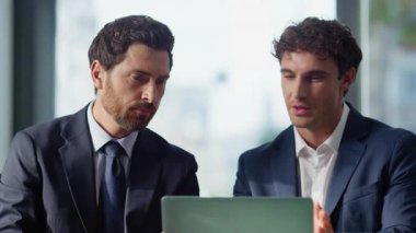 Panoramik kafe kapanışında dizüstü bilgisayara bakan konuşan ortaklar. Profesyonel iş arkadaşları proje üzerinde ortaklaşa çalışma stratejisini tartışıyorlar. İş arkadaşları restoran masasında takım çalışması yapıyor.