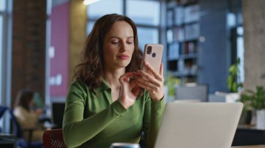 Ofiste cep telefonu mesajlaşmasını kutlayan mutlu bir işçi. Dizüstü bilgisayarda çalışan genç iş kadını akıllı telefon bildirimi okuyor. Gülümseyen müdür cep telefonuyla başarıyı kutluyor. 