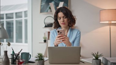 Akıllı telefondan mesaj alan kafası karışmış bir çalışan ofis çalışma masasında dizüstü bilgisayarla yakın çekim yapıyor. Tatminsiz kadın yönetici iş yerinde cep telefonundan SMS okuyor. İş kadını sorun üzerinde düşünüyor