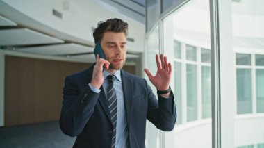 Kızgın patron cep telefonu diye bağırıyor modern ofis koridorunda yürüyor. Sinirli bir yönetici şirket koridorunda duygusal jestler yaparak tartışıyor. İş adamı telefon konuşmasından memnun değil