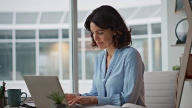 Modern ofis iç mekanında dizüstü bilgisayarı yazdıktan sonra kağıtları kontrol etmekle meşgul. Belgelerde motivasyonsuz profesyonel muhasebeci hatası var. Bilgisayar işyerinde çalışan iş kadını.