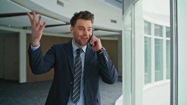 Koridordaki pencerelerde yürüyen mutlu yönetmen konuşuyor. Heyecanlı bir yönetici telefon konuşmasından keyif aldığını ve belgeleri attığını ifade ediyor. Kendine güvenen işadamı cep telefonuyla harika haberler paylaşıyor..