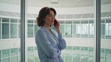 Ofis penceresinin önünde cep telefonuyla iletişim kuran bayan patron zoom 'u kapat. Modern şirket koridorunda şık bir iş kadını akıllı telefonu arıyor. İş molasında kendine güvenen bir kadın cep telefonu konuşması..