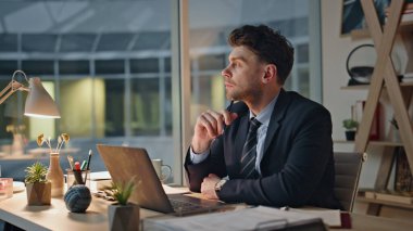 Düşünceli iş adamı akşam ofisinde dizüstü bilgisayarı inceliyor. Çalışma masasında oturarak iş geliştirmeyi düşünen ciddi bir gece çalışanı. Dalgın girişimci fazla mesai ile görevleri çözüyor. Kariyer konsepti