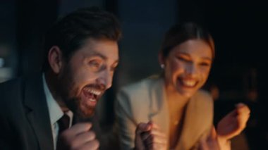 Fazla mesai çalışanları, gece ofis portresi için sevinçten havalara uçuyor. Gülümseyen iş kadını, neşeli iş adamına beş kez yakın çekim yapıyor. İş ortakları duygusal açıdan başarılı oldu