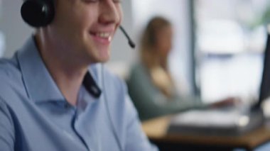 Yardım masası operatörleri kulaklık takarak konuşuyor. Ofisteki müşterilere yakın çekim yapıyorlar. Birkaç satış müdürü online hizmet öneriyor. Yardım hattında çalışan gülümseyen çalışanlar.