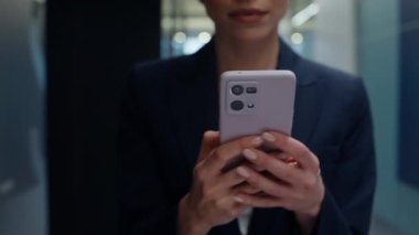 Modern giriş kapısında cep telefonu tutan iş kadını elleri var. Zarif bayan patron boş ofis koridorunda internetten akıllı telefon içeriğini izliyor. Koridorda cep telefonuyla mesajlaşan bir kadın.
