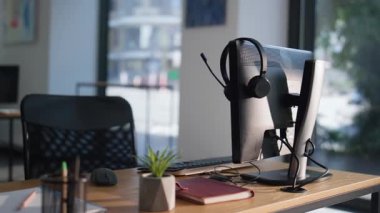 Boş çalışma alanı, bilgisayar monitörü ve ahşap masadaki kulaklıklar. Organize ofis açık alanı üretken bir atmosfer yaratıyor. Müşteri hizmetleri desteği için profesyonel modern işyeri.