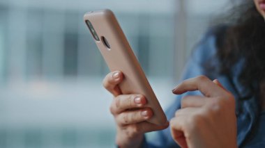 Yakından cep telefonu ekranına dokunuyor. Rahat bir kadın internet üzerinden internet alışverişi yapıyor. Gülümseyen güzel bayan kayan akıllı telefon sörfü. Dijital cihaz kullanan kıvırcık esmer..