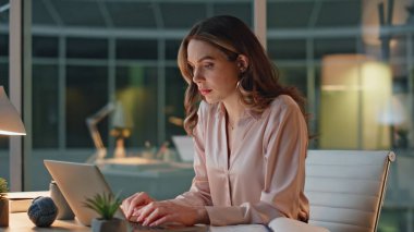 Karanlık ofiste bilgisayarlara bakan bir kadın. Yorgun bir kadın dizüstü bilgisayarı kapatıyor iş yerinde yorgunluk stresi yaşıyor. Geceleri laptopla çok çalışan bir çalışan. Şirket çalışanı iş hayatını başarıyla tamamladı.