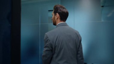 İş adamı tek başına koridoru geçiyor. Resmi takım elbiseli, sakallı, rahat bir çalışan. Gri vestibül 'de iş arkadaşlarını selamlıyor. Sakin yönetmen boş şirket binasına basıyor.