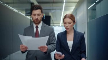 İki patron sözleşmeli yürüyüş koridorunu tartışıyor. Yakın çekim. Hayal kırıklığına uğramış iş kadını, ekranı iş adamına gösteren cep telefonu uyarısına tepki veriyor. Sinirli iş çifti para kaybediyor