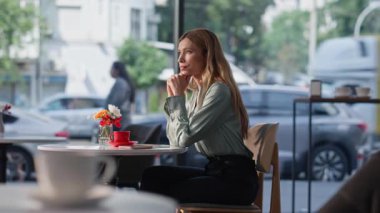 Kafe masasında oturan yalnız kadın rüya gibi bir yüz ifadesiyle. Dost canlısı restoran garsonu boş kahve fincanı alan bayan müşteriye servis yapıyor. Düşünceli sarışın kadın hayatı düşünüyor. Rahat kafeteryada yalnız başına dinleniyor..